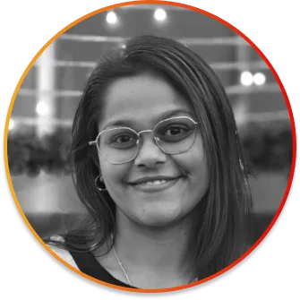 Portrait of a smiling woman with shoulder-length dark hair and glasses, framed by an orange gradient circular border.
